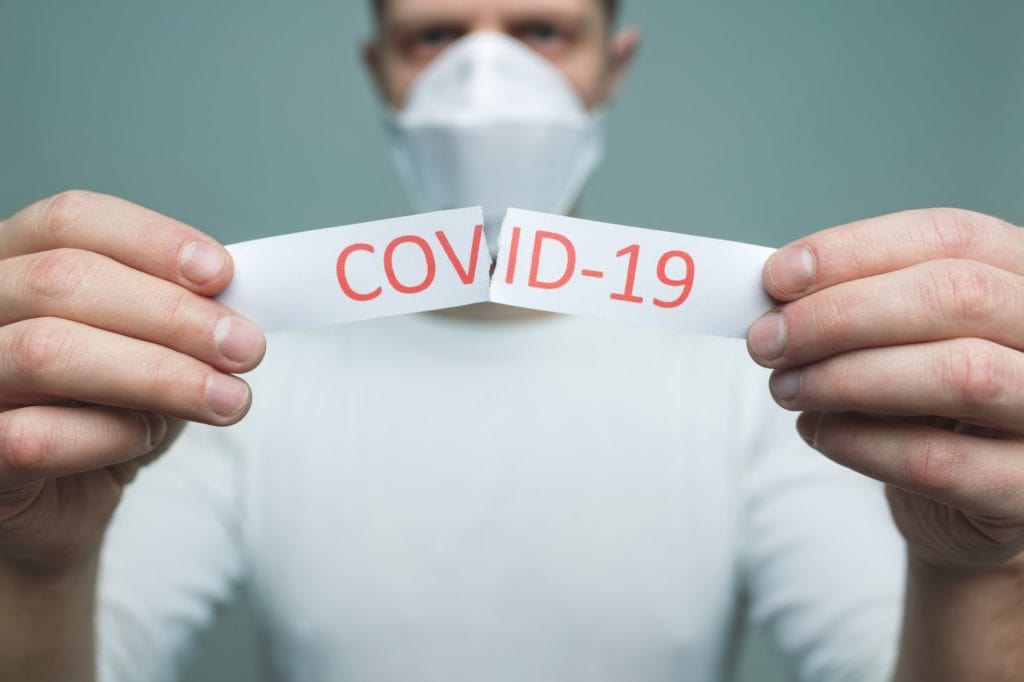 Man wearing a respiratory mask, holding the Coronavirus Covid-19 sign